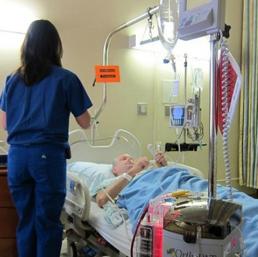 un anziano allettato in ospedale, mentre viene assistito dal personale sanitario